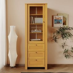 a tall wooden cabinet sitting next to a plant in a room with beige walls and flooring