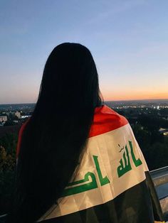 the back of a woman's head as she stands in front of a cityscape