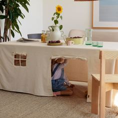 a person sitting under a table with a small house on it's back end