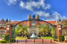 a large building with a fountain in front of it and palm trees around the entrance