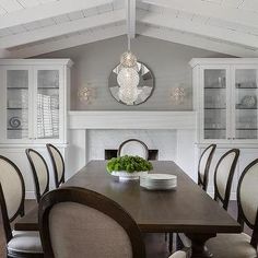 a dining room table with chairs and plates on it, in front of a fireplace