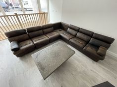 a large sectional couch sitting on top of a hard wood floor next to a window