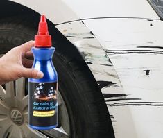 a hand holding a bottle of cleaner next to a car tire