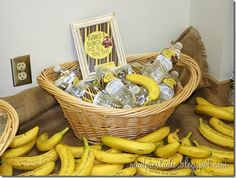 some bananas are sitting in a basket on the floor next to water bottles and cards