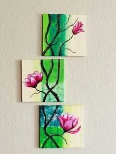 three pieces of art hanging on the wall with flowers painted on them, one is pink and green