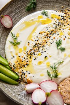 a plate topped with cucumbers, crackers and sour cream sauce next to sliced radishes