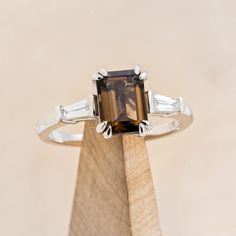 a brown and white diamond ring sitting on top of a wooden stand