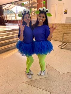 two girls dressed in costumes standing next to each other on the floor with their hands up