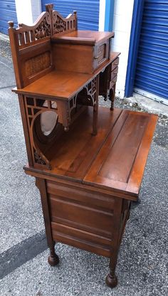 an old wooden desk with a clock on it's top and bottom shelf, sitting in front of a blue garage door