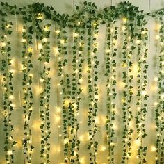 a bed covered in lots of green plants next to a wall with lights on it