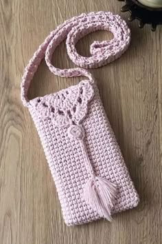 a pink crocheted purse sitting on top of a wooden floor next to a clock