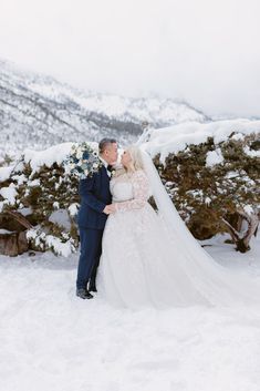 a bride and groom standing in the snow with their arms around each other as they kiss