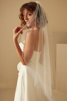 a woman in a wedding dress is holding her veil over her face