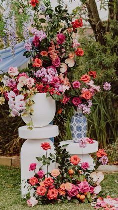 an arrangement of flowers in vases sitting on top of each other