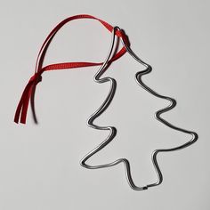 a metal christmas tree ornament hanging from a red ribbon on a white background