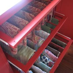 the drawers are filled with many different colored fabrics and pillows, including one in red