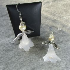 These Christmas Angels have a long white skirt made from a frosted white Lucite flower bead, with a white glass pearl beneath. The wings are Zinc Alloy while the neck is a silver coloured metal bead above this is a head of a white frosted glass bead and a halo of crystal and silverplate. The earwire is stainless steel and the earrings come enclosed within an organza bag. Elegant White Christmas Jewelry, Elegant White Jewelry For Christmas, Elegant White Christmas Earrings, Angelic White Jewelry For Gifts, Long White Skirt, Jade Bead Necklace, White Long Skirt, Angel Earrings, Graduation Necklace