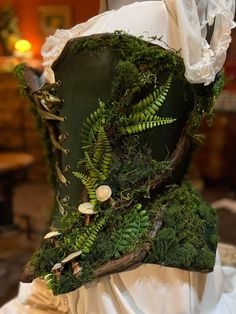 the back of a wedding dress covered in green plants and ferns, with buttons on it