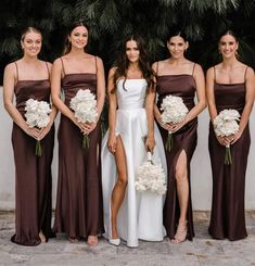 a group of women standing next to each other wearing dresses and holding bouquets in their hands