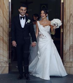 a bride and groom holding hands walking out of the church door after their wedding ceremony