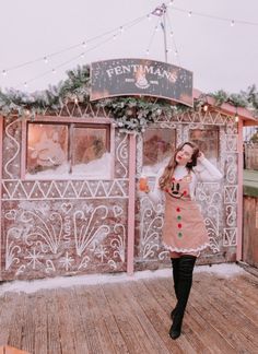 a woman standing on top of a wooden deck in front of a building covered in snow