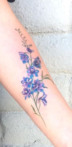 a woman's arm with purple flowers on it and the word love written in cursive writing