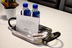 two bottled water bottles sitting on top of a metal tray next to a flower pot