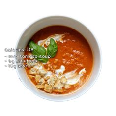 a white bowl filled with tomato soup and garnished with basil leaves on top