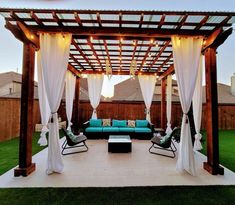 an outdoor living area with white curtains and blue couches in the middle of it