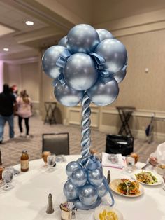 a table topped with balloons and plates of food on top of a white table cloth