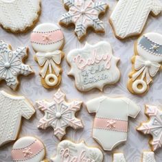 decorated baby shower cookies are displayed on a white tablecloth with snowflakes and mittens