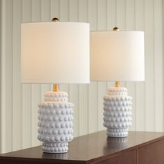 two white lamps sitting on top of a wooden table