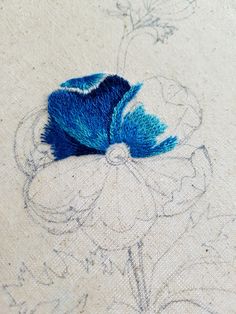 a close up of a piece of cloth with blue thread on it and a flower