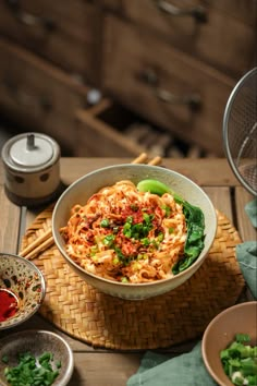 a bowl filled with noodles and vegetables on top of a wooden table next to chopsticks