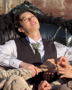 a young man sitting in a chair with his eyes closed and hands on the tie