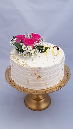 a white cake with pink flowers on top sitting on a gold plated platter