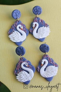 four white and blue swan shaped earrings on a yellow surface