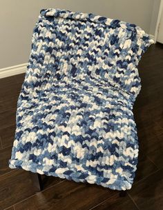 a blue and white blanket sitting on top of a wooden floor