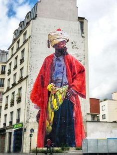 a large mural on the side of a building with a man standing in front of it