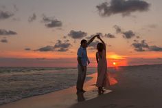 a man and woman dancing on the beach at sunset