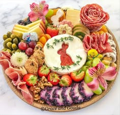 a platter filled with cheese, meats and fruits on a marble counter top