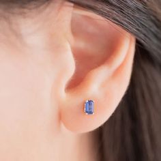 a woman's ear is shown with a blue stone in the shape of a square