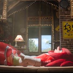 a woman laying on top of a giant red object in front of a brick building