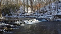 a small waterfall in the middle of a snowy forest