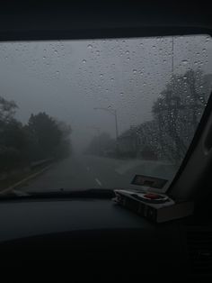 rain drops on the windshield of a car as it drives down a road in the rain