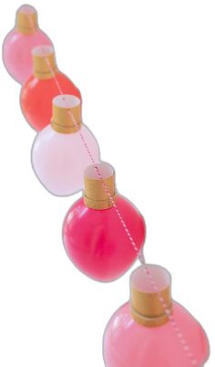 pink and red perfume bottles are lined up on a string with gold trimmings