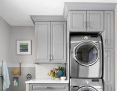 a washer and dryer in a small room with gray cabinets on the walls