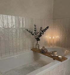 a white bath tub sitting next to a wooden shelf with candles on top of it