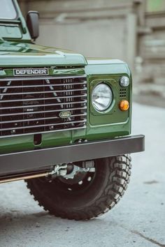 the front end of a green truck parked on top of a sidewalk