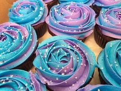 blue and purple cupcakes with sprinkles on them in a box